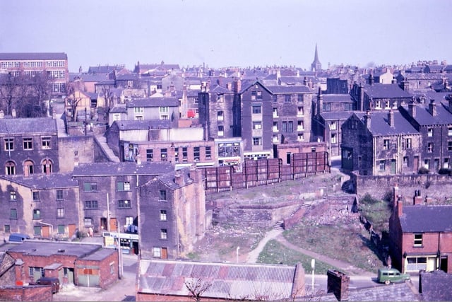 A view overlooking Morley Bottoms taken from Troy Road in April 1962. The image shows how the valley slopes have been built on from Bank Street to Chapel Hill and to Station Road. Demolition has taken place, during the inter-war years, of shops on Chapel Hill (now replaced by rusty advertising hoardings), of housing around the steps from Chapel Hill to Station Road, and in Red Lion Yard in the foreground. Some of the buildings by the paper shop on Station Road disappeared shortly after this picture was taken, as did the Carrier's Arms and houses in Webster's Yard. The Prospect Mills (left) and St. Peter's Parish Church (right) break the horizon.