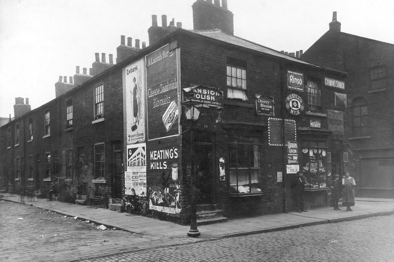 A view taken from junction of Regent Street with Mason Street in June 1926. Business on left is 64 Regent Street with 62 Regent Street on the right, the business of Mrs Minnie Ellis, Shopkeeper. Junction with Cloth Street is just visible. Man, Woman and child stand on pavement.
