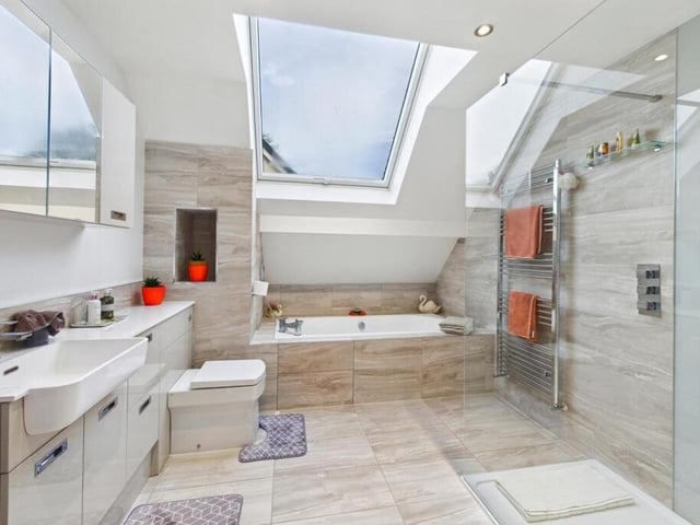 The bathroom has a four-piece suite comprising of a large walk-in shower, a bath with a tiled surround with a mixer tap and shower attachment, a low flush w.c and a wash hand basin set into high gloss vanity cupboards.