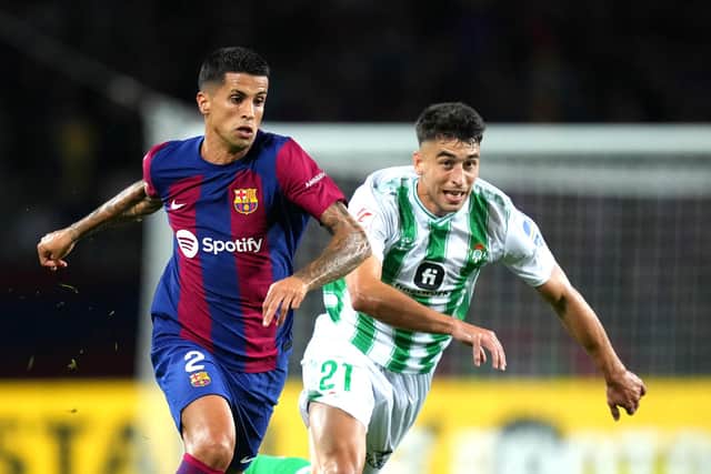 BARCELONA, SPAIN - SEPTEMBER 16: Joao Cancelo of Barcelona runs with the ball whilst under pressure from Marc Roca of Real Betis during the LaLiga EA Sports match between FC Barcelona and Real Betis at Estadi Olimpic Lluis Companys on September 16, 2023 in Barcelona, Spain. (Photo by Alex Caparros/Getty Images)