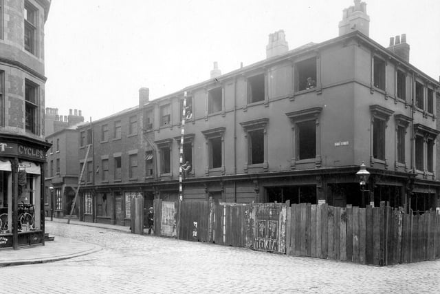 A view of the junction of Woodhouse Lane with Wade Street. Properties on right are derelict. Workmen stand with measuring pole. Pictured in August 1906.