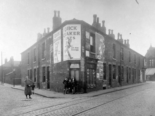 In the centre is number 10 Mrs Selina Lampey, shop and Times Sanitary Steam Laundry. There are posters advertising Quick Quaker Oats and Lyons Tea. Pictured in August 1930 .