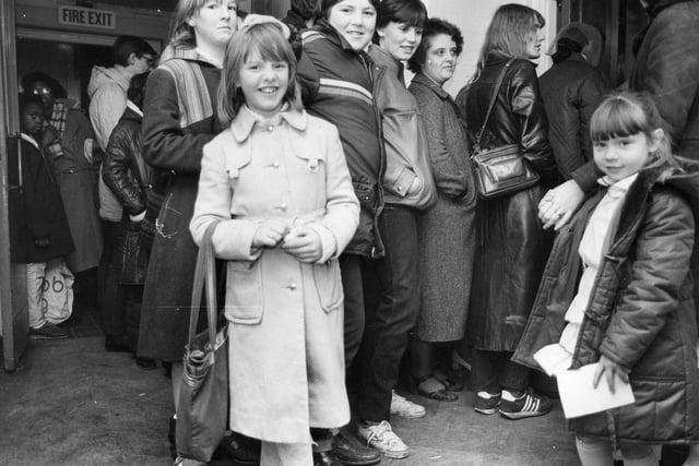 Another photo taken outside Wykebeck School where people are queuing for the annual Wykebeck 'Family Allowance Toy Fair' held in December 1984. It was an opportunity to buy Christmas toys at reasonable prices thanks to donations by local firms and business fairs including 'Toy City'. The toys were a joint initiative between Social Services, the Probation Service and the Tenants' Association.