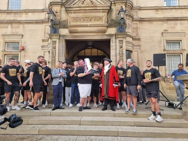 Trinity owner Matt Ellis kisses the Super League trophy outside the town hall.
