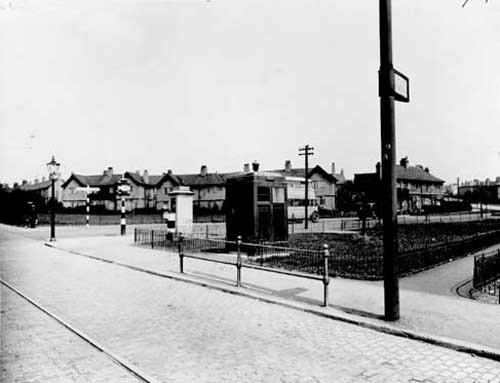 The junction of Stainbeck Road and Meanwood Road, which is on the left of the view. Scene includes a street lamp and a finger signpost pointing to Headingley towards the left, Chapeltown and Moortown going right. A traffic light, telephone box, tram stop and barrier can be seen. Also a police box which is in the centre. It was used by the police on patrol to call the police stations, before personal radios were available.