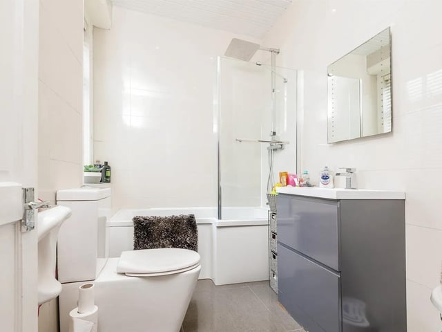The modern fully tiled bathroom suite comprises of L shaped bath with shower over.