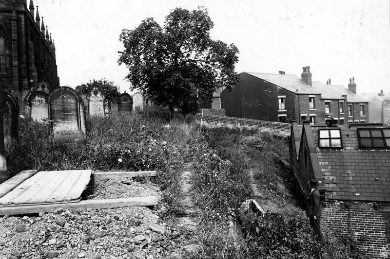 View across the graveyard of St Mark's Church. On the far left is the church, then some gravestones, (including a prominent one for three members of the Marshall family). The ground then drops steeply away towards some houses, where a man is standing. Pictured in July 1942.