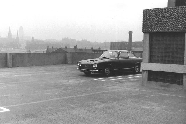 This photo was taken from the top of the Merrion Centre multi-storey car park looking across in the direction of Woodhouse Lane. The three church spires belong to Emmanuel, left, Trinity, centre, and Blenheim Baptist Church, right. The silhouette of University's Parkinson building is visible in the background. The rooftop just showing behind the Bristol motorcar is the Cobourg Tavern at the junction of woodhouse Lane with Claypit Lane.