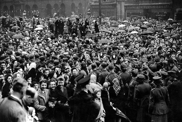 Dense crowds on The Headrow and Victoria Square, in front of Leeds Town Hall. They are waiting for the Victory Parade to begin, part of the VE celebrations in May 1945.