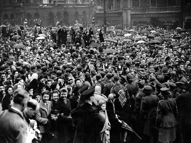 Dense crowds on The Headrow and Victoria Square, in front of Leeds Town Hall. They are waiting for the Victory Parade to begin, part of the VE celebrations in May 1945.