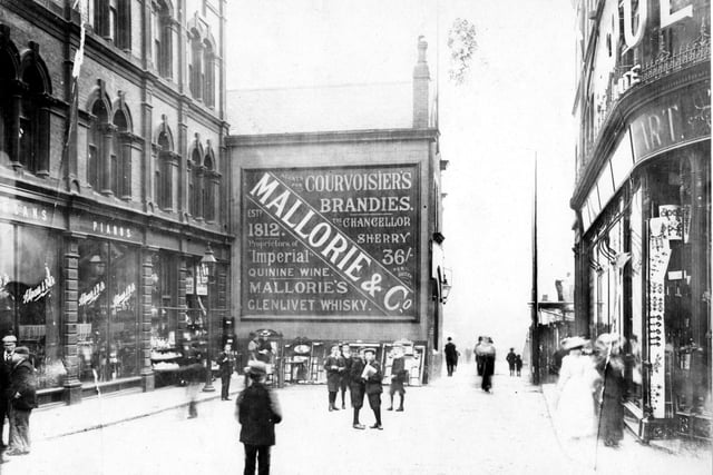 Lands Lane looking south from Upperhead Row in September 1898. Shops include an organ and piano shop and Mallorie and Co selling wines, spirits and sherry. Scaffolding on right for Victoria Arcade.