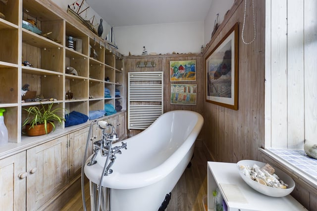 A free standing slipper bath dominates this panelled bathroom.