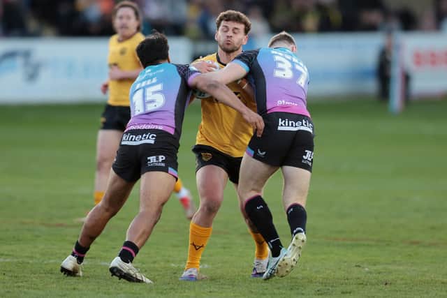 Castleford Tigers' George Lawler is tackled by James Bell and Harry Newman of Hull FC. Picture by John Clifton/SWpix.com.