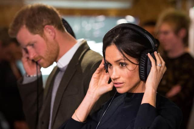 Prince Harry and Meghan Markle listen to a broadcast through headphones during a visit to Reprezent 107.3FM community radio station in Brixton in 2018 (Photo: DOMINIC LIPINSKI/AFP via Getty Images)