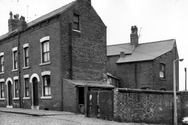 Double fronted terraced houses on Aysgarth Mount pictured in September 1966.  On the right is the lean-to originally built to house the shared toilets, now used to store dustbins since the advent of indoor plumbing. On the right is the gated entrance to the yard with the cobbled road entrance to Back Aysgarth Mount.