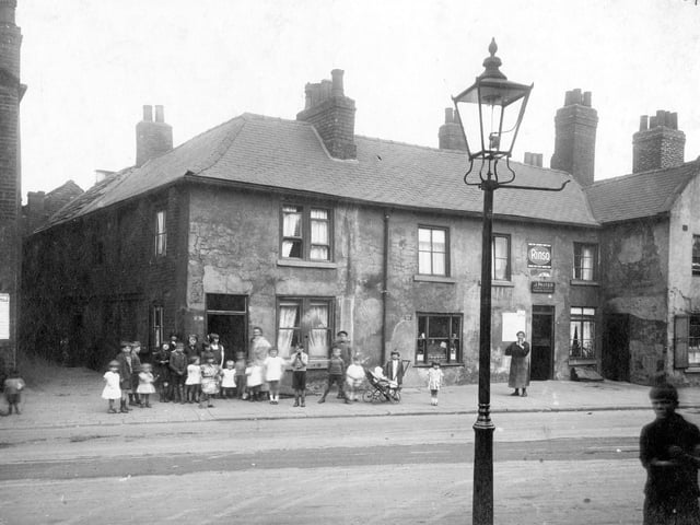Children and woman pose outside buildings and entrance to Taylors Place in August 1929. The shop to the left is number 10 Church Street and the premises of John Porter, tobacconist.