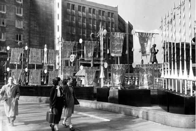Two schoolgirls stroll past Coronation decorations on City Square. The Queens Hotel is in the background.