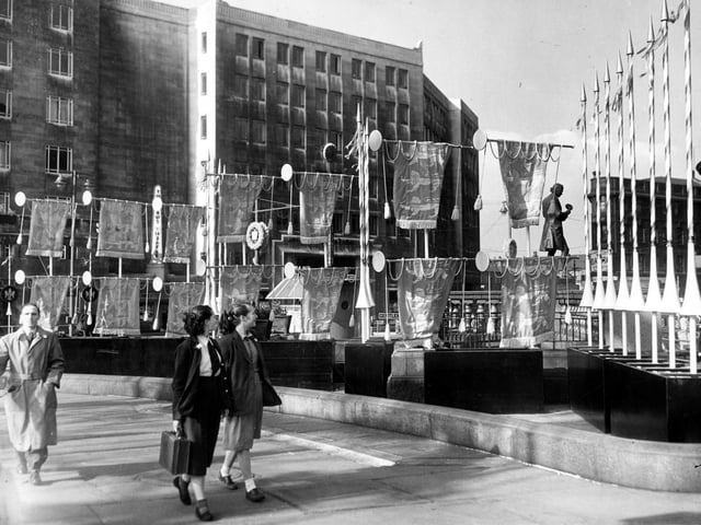 Two schoolgirls stroll past Coronation decorations on City Square. The Queens Hotel is in the background.