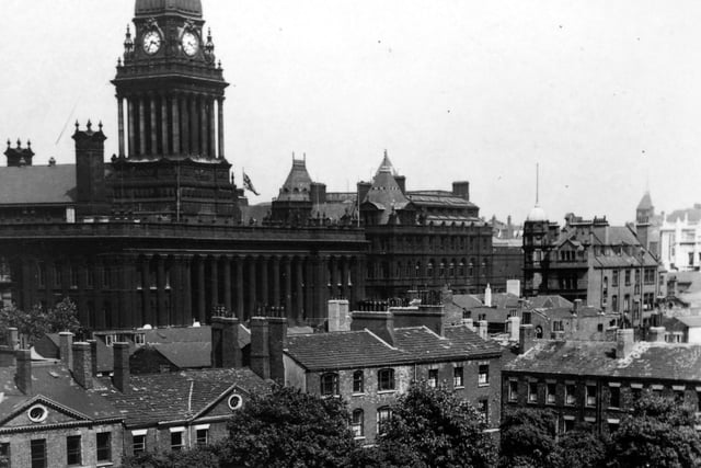 Park Square with Leeds Town Hall in the background pictured in July 1947. Running across the centre are Georgian buildings situated in Park Square North and at the right edge those in Park Square East. The square appears to have unmade paths, sparse grass and mature trees. Nowadays, the buildings are restored and the square is laid out with paths, flower beds and seating.