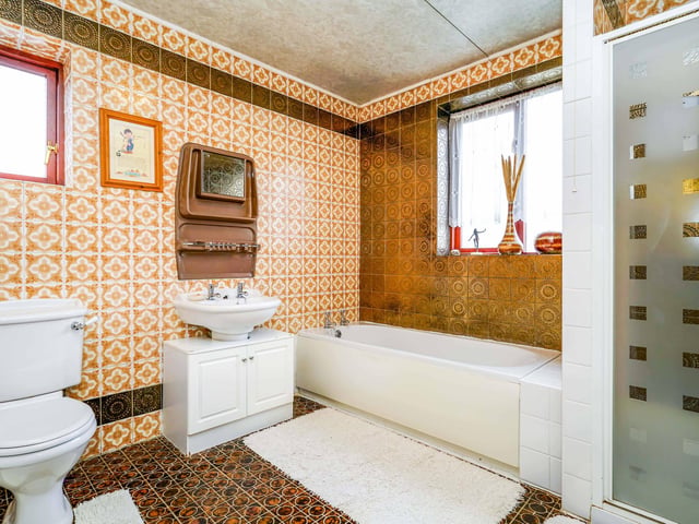 Upstairs, there are three bedrooms and an airy bathroom with a bath and shower unit.