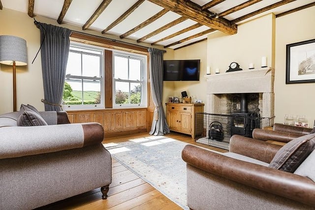 A stove within a large stone firepace is a feature of this sitting room with a stunning vista