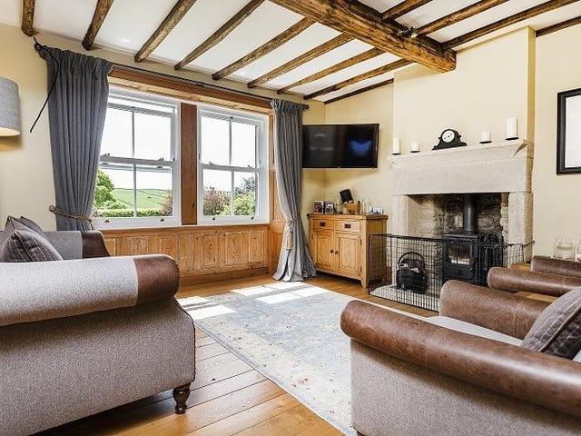 A stove within a large stone firepace is a feature of this sitting room with a stunning vista