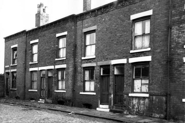 Ascot Avenue in October 1966. The image shows front of through terraced houses. The pavement is overgrown with weeds and the windows of number 110 on the left have been smashed.