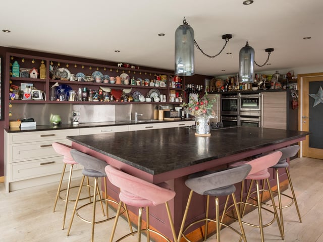 The open plan kitchen has an extensive breakfast bar with a Neff induction hob and a black riven granite worktop. A wall of units has integrated appliances including three Neff ovens, a microwave oven and a warming drawer.