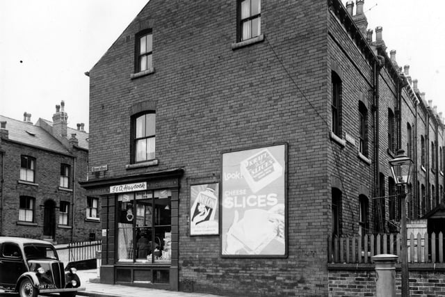 Haycock's Grocers on Queen's Road pictured in July 1956. Howden Place is on the left and Howden Street on the right. Adverts for Nulon Hand Cream and Kraft Cheese Slices are visible.