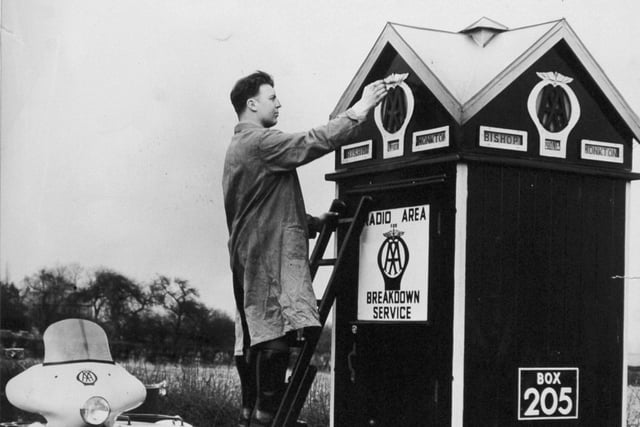 AA patrolman C. Stanway makes the best of the fine weather as he gives a spring coat of paint to the Bishop Monkton box, on the A61 to Ripon in March 1961.