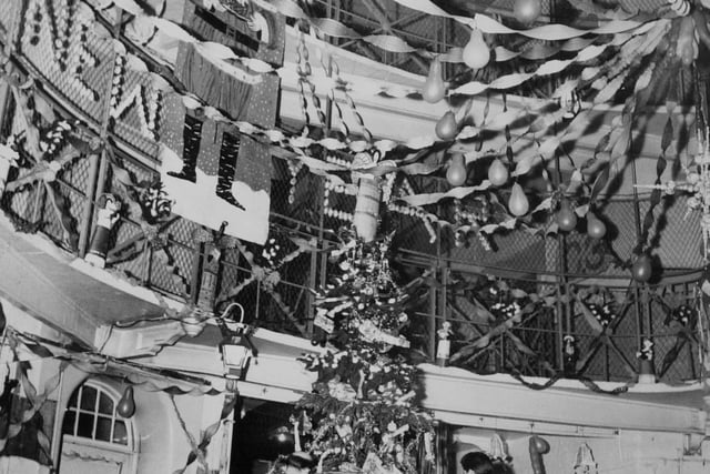 The decorated centre of Leeds Prison in December 1963. In the centre is the Christmas tree hung with make believe parcels. Bare lamp bulbs are covered with cardboard lanterns. An ingenious sputnik "mobile" is on the extreme right.