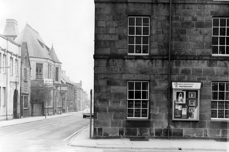 Boroughgate of the junction with Wesley Street in July 1979. On the right is Atkinson, Dacre & Slack, solicitors. A display board for Edward A Winpenny, photography, whose business is around the corner on Wesley Street, is on the wall. On the left are offices of Otley Building Society, then Garrant Copier Services, a 'To Let' building and the junction with Courthouse Street.