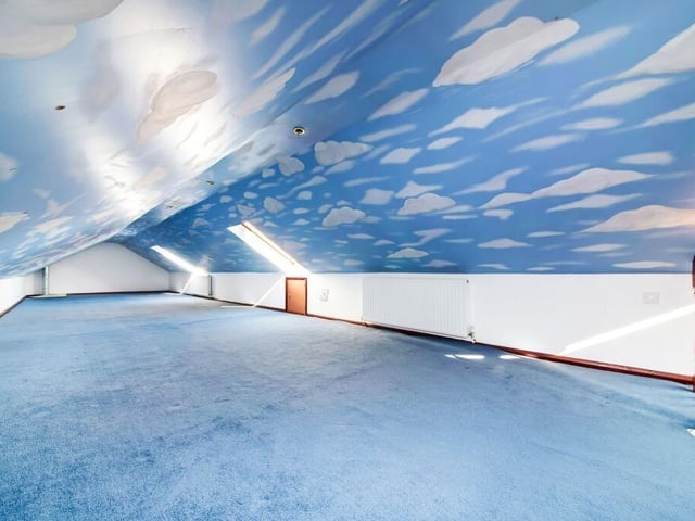 An upper floor play room with a 'sky and clouds' ceiling.