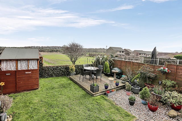 The rear garden provides ample space with a grassy area and decking alongside the shed.