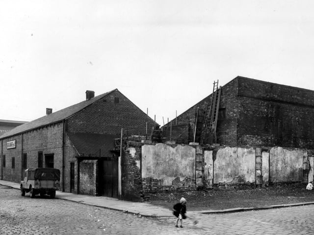 Orchard Street runs from the left this view with the premises of Leeds Cleaning Co (Building) Ltd visible. On the right is Aloe Street, children play in the rubble of recently cleared property. The back of Central Motor Auctions is visible on the right. Pictured in August 1958.