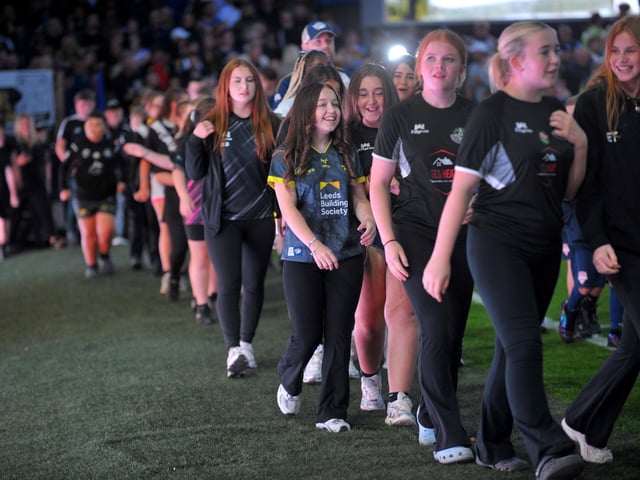 Flag wavers enter the pitch before Leeds Rhinos' game against Wigan Warriors.