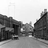This view looks north east towards Domestic Street. On the left is Bridge Motors, with a man outside with a horse and cart. A row of brick terrace houses with outside toilet yard runs along the right. At the bottom of the street with its gable end facing, is Geo. Ledsford butchers and a shop in the name of Nixon? Pictured in May 1951.