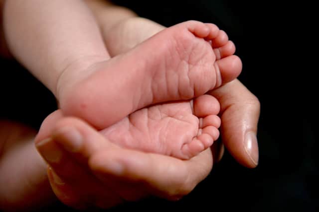 Undated file photo of a a mother holding the feet of her new born baby in her hand. Andrew Matthews/PA Wire