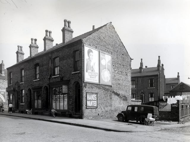 Oatland Avenue is to the left, next 100 Camp Road is empty, it had been a newsagents shop run by H. Crawford. Then 98 is a house, 96 has a shop window. On the right, 94 is a tailors shop, also offering garment alterations, cleaning and pressing. Woerth Place is on the right, the house in view is number 14 Oatland Avenue. A clothing factory on the right edge has notices, promising top wages, no short time also hands wanted. Pictured in July 1958.