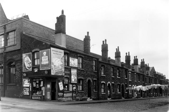 Binks Street from the junction with Armley Road in August 1958. This was located next to Brancepeth Place. On the left is a grocers shop on Armley Road. Posters on the walls promote films including 'A Night to Remember' showing at the Odeon, a drama depicting the fate of the Titanic starring Honour Blackman, and 'The Whole Truth' at the Majestic starring Stewart Granger, Donna Reed and George Sanders.  Backing onto the houses on the far left is the works of Greenwood and Batley Ltd., engineers.