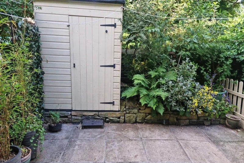 The back garden offers a private oasis, with lush greenery and space for potted plants.