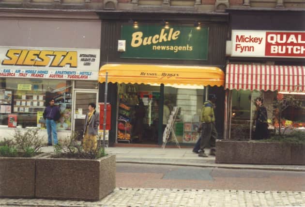 Shops on  The Headrow in August 1991. From left is Siesta Holidays, then Buckle newsagents and Mickey Fynn butchers.