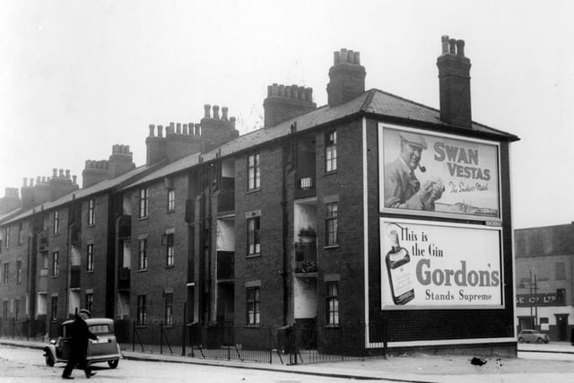 Marsh Lane Tenements pictured in August 1939. They were built in the early 1900s, to rehouse tenants of slum properties in this area, which was classed as one of the unhealthy districts. This was one of the first purpose built blocks of flats in Leeds, 2 and 3 bed room units, housed 198 people. They were built by private enterprise. End wall carries posters advertising Swan Vestas matches and Gordons Gin.