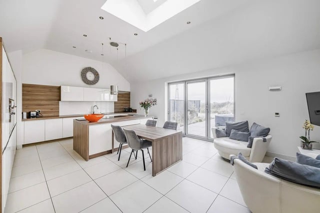 The family dining kitchen is a sociable living space with a vaulted ceiling and boasts an extensive range of contemporary high gloss units fitted at floor and wall height.