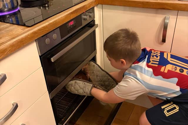 Charlie carefully places a cake in the oven for the charity bake sale.