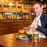 Royal butler eating a burger with a knife and fork
