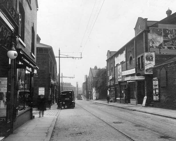 Town Street in June 1931. On the left, part of display window for Maypole dairy number 192 which has a white lamp outside. Next number 190 premises of Miss Hilda Baltye, ironmonger. Entrance to Spring Street can be seen. In the road a Co-op bakery delivery vehicle is parked outside store. On the right is the Lido Cinema. Built in 1912 as the Palace. In 1929 talking pictures arrived, the cinema was refitted and the name was changed to the Lido. In this photograph, Ken Maynard is starring in 'Sons of the Saddle'. On the gable end, a poster advertises 'Outside the Law' starring Mary Nolan. To the right of the cinema, a notice board gives details of shopping facilities in Bramley, the board shaped like a gothic window is advertising Leeds Permanent Building Society.