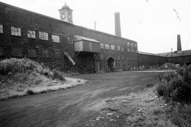 The mill's outer courtyard in July 1963. The four storey building incorporates some of the oldest parts of the mills, dating from 1792/93. The wooden structure which juts out at third floor level was intended to let in additional light for the mending process.