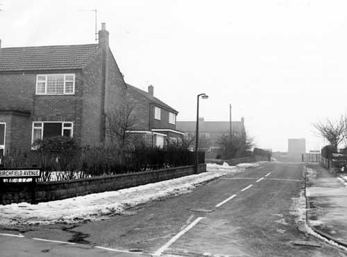 Street Lane at the junction with Birchfield Avenue. The house on the left is numbered 50a Street Lane; behind that is number 1, Birchfield Avenue. In the background on the right is Gildersome Birchfield Primary School. Pictured in February 1980.
