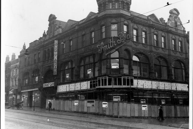 Improvement works to The County Arcade, Smith Brothers, Smith Brothers was a large premises and in the photo, it is shown with scaffolding and hoardings surrounding it. The illuminating 'Smith Brothers' sign is visible on the corner of the building where Queen Victoria Street starts.